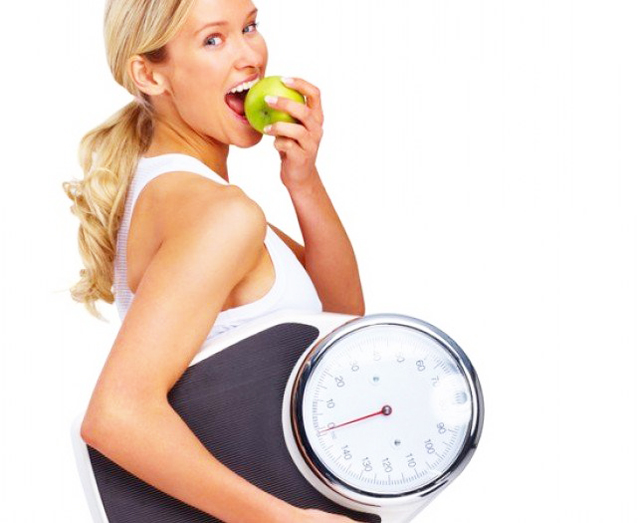 Woman holding scales and eating an apple