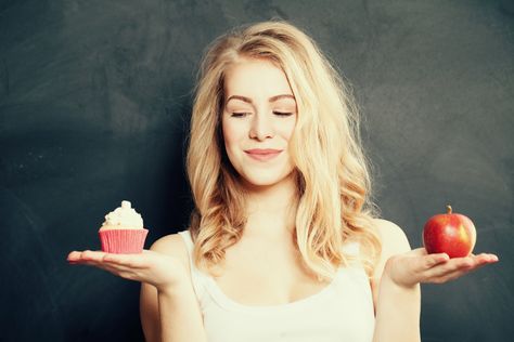 Woman choosing between apple and cupcake
